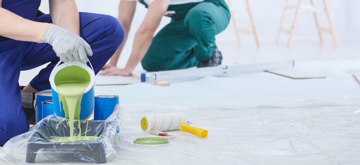 House painter pouring green wall paint into tray