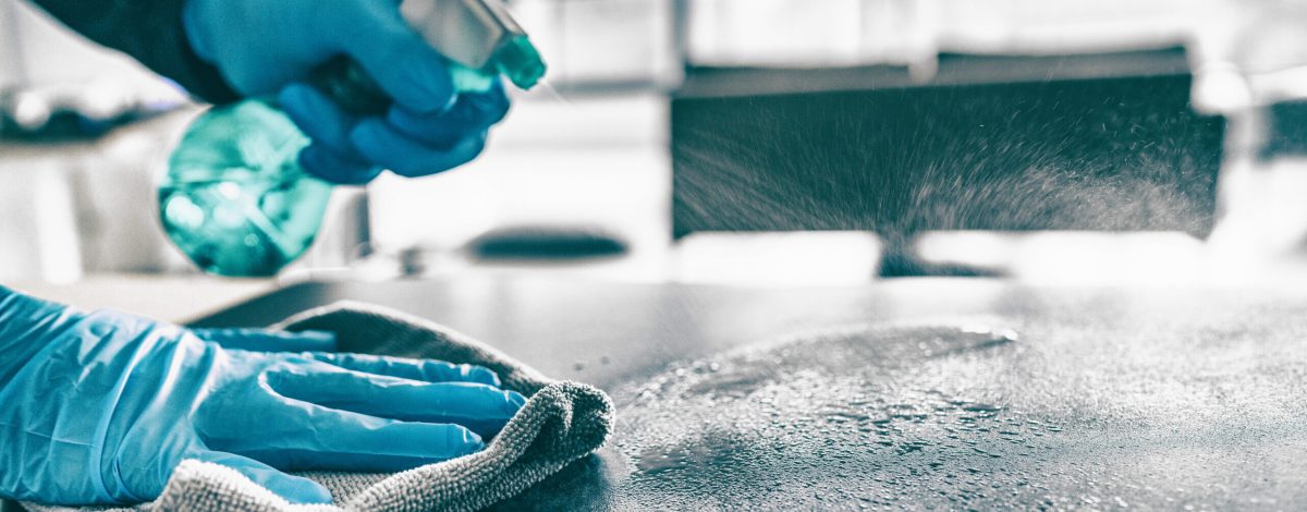 Cleaning home table sanitizing kitchen table surface with disinfectant spray bottle washing surfaces with towel and gloves. COVID-19 prevention sanitizing inside.